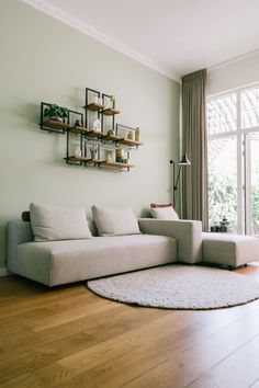 a white couch sitting on top of a hard wood floor next to a wall mounted shelf