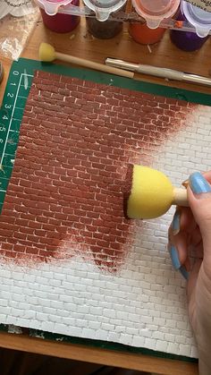 a person using a brush to paint a brick wall