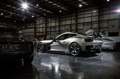 two cars parked in a garage next to each other with their doors open and lights on