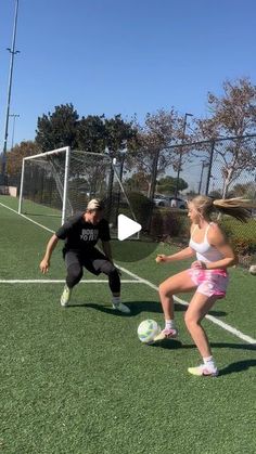 two girls are playing soccer on the field