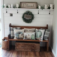 a wooden bench with pillows on it in front of a white wall and wood floor