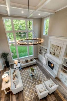 an aerial view of a living room with couches, fireplace and large windows in the background