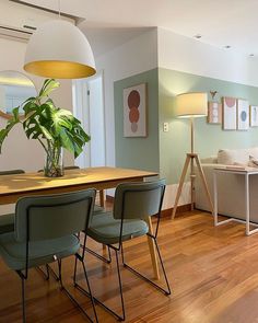 a living room filled with furniture and a wooden dining table surrounded by green chair covers