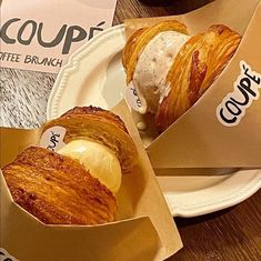 two croissants with ice cream and coffee in paper containers on a table