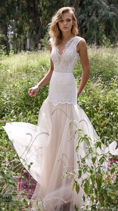 a woman is standing in the grass wearing a wedding dress with lace and tulle