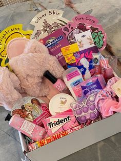 a pink teddy bear sitting inside of a box filled with lots of different types of items