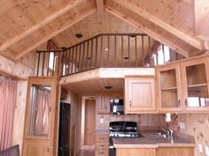 a kitchen with wooden walls and flooring next to a lofted ceiling above a stove top oven