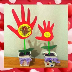 two handprints with flowers in them are on a table next to some hearts