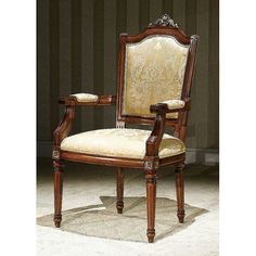 an ornate wooden arm chair with beige upholstered fabric seat and back, in front of striped wallpaper