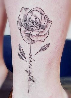 a black and white rose tattoo on the side of a woman's leg, with words written in cursive writing