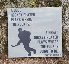 a sign on the side of a tree that says, a good hockey player plays where the puck is