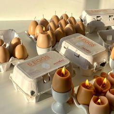 eggs and candles are sitting on a table next to an egg carton with six eggs in it