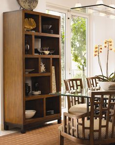 a dining room table and chairs in front of a bookcase with glass doors on it