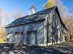 a large gray barn with two garages and a steeple