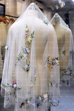 two mannequins covered in white veils with flowers on them and one wearing a dress