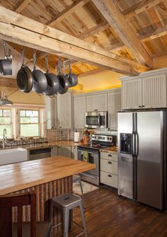 a kitchen with an island and pots hanging from the ceiling