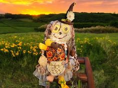 a scarecrow doll sitting on a bench in the middle of a field at sunset