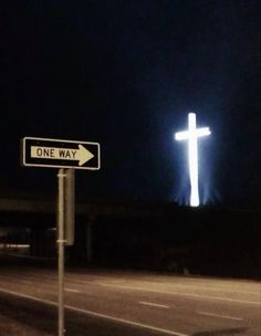 a street sign with a cross on it at night