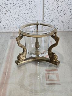 a glass with a metal stand on top of it sitting on a marble countertop