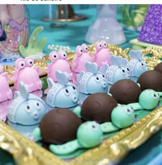 there are many little toy animals in the tray on the table with blue and purple decorations