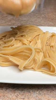 a white plate topped with pasta on top of a counter