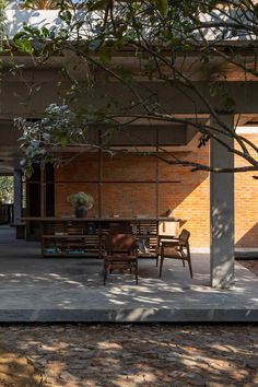 an outdoor dining area with tables and chairs under the shade of a large leafy tree