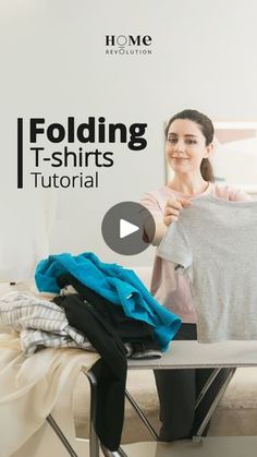 a woman holding up a t - shirt while standing next to a ironing board