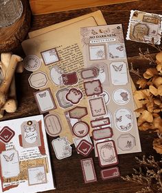 some papers and stickers sitting on top of a wooden table next to dried flowers