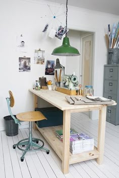 a room with a desk, chair and hanging light in it's center area