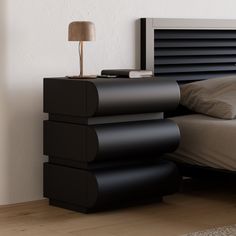 a bed with a black headboard next to a night stand and lamp on top of it