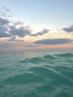 the ocean is very choppy and blue with some clouds in the sky above it