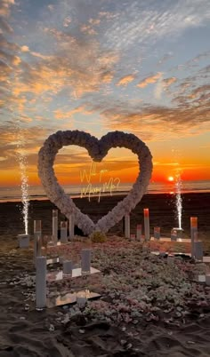 a heart made out of flowers sitting on top of a beach