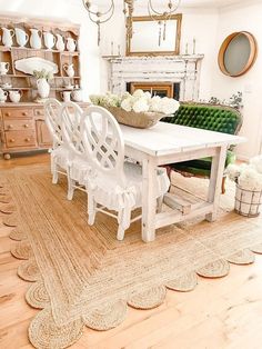 a white table and chairs in a room with wooden floors, chandelier and fireplace