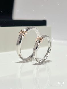 two white gold wedding rings with diamonds on the inside and outside, sitting on a table