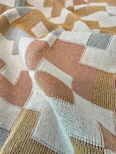 an orange, white and brown abstract design on a fabric with small squares in the center