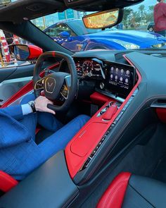 a man sitting in the driver's seat of a red and black sports car