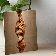 a spiral wooden sculpture sitting on top of a table next to a potted plant