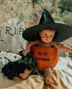 a baby wearing a witches hat sitting on top of a pumpkin