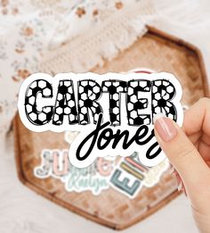 a hand holding up a sticker that says,'carter jones'in black and white