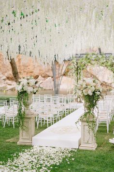 an outdoor ceremony setup with white chairs and flowers