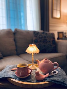 a table with two cups and a teapot on it in front of a couch