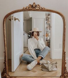 a woman sitting on the floor in front of a mirror