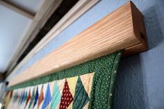 a close up of a wooden frame on a wall with colorful quilts hanging from it