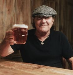 a man sitting at a table with a glass of beer