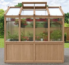 a small wooden greenhouse with plants in the windows and doors on it's sides