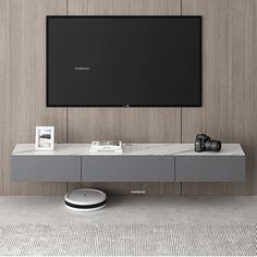 a flat screen tv mounted to the side of a wall next to a gray table