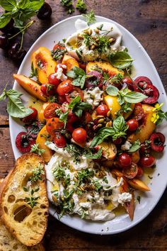 a white plate topped with lots of food on top of a wooden table next to bread