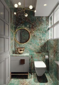 a bathroom with green marble walls and flooring, including a white toilet and sink