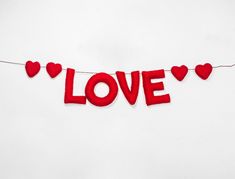 the word love is spelled with red felt hearts on a white background to spell out valentine's day