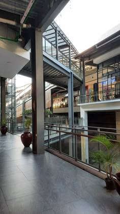 the inside of a large building with lots of windows and plants in pots on the floor